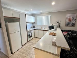 a kitchen with a white refrigerator and a counter top at Beachside Townhouse Bunbury in Bunbury