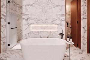 uma banheira branca na casa de banho com uma parede em mármore em Grand Hyatt Kuwait em Kuwait