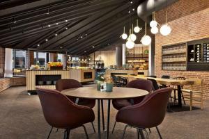 a restaurant with tables and chairs and a kitchen at Comwell H C Andersen Dolce by Wyndham in Odense