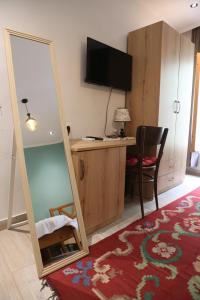 einen Spiegel in einem Zimmer mit einem Schreibtisch und einem TV in der Unterkunft Agora Bed & Breakfast in Vlorë