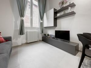 uma sala de estar com uma televisão e um sofá em Realkasa Benedetto XIV em Bolonha