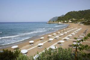 a beach with umbrellas and chairs and the ocean at Ella Elyra - Adults Only in Pelekas