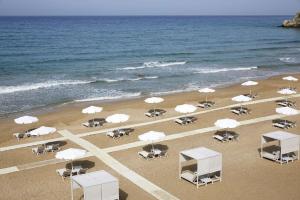 a beach with white umbrellas and chairs and the ocean at Ella Elyra - Adults Only in Pelekas