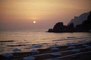 a beach with umbrellas and the ocean at sunset at Ella Elyra - Adults Only in Pelekas +48 photos