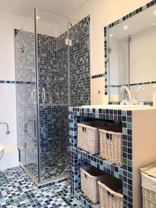 een blauw betegelde badkamer met een douche en een wastafel bij Spacious and light flat with beautiful views in Santander
