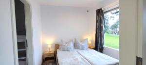 a bedroom with a white bed with a window at Bungalow Ückeritz in Ueckeritz