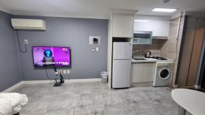 a kitchen with a refrigerator and a tv on the wall at Dusil Subway Station One-Bedroom Apartment in Busan