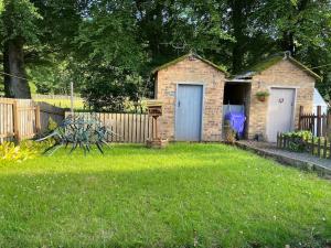 a small brick building with a shed in a yard at Lovely little house in Yarrowford - Yarrow Valley in Broadmeadows