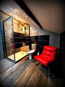 La salle de bains est pourvue d'une chaise rouge et de toilettes. dans l'établissement PLAISIR DES SENS, à Roanne
