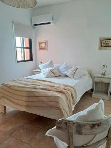 a white bedroom with a large bed and a chair at Apartamento Rufina VII pleno centro San Luis in San Luis
