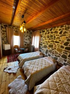 sypialnia z 4 łóżkami i kamienną ścianą w obiekcie Ballkon Turi w Tiranie