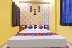 a bedroom with a large bed with blue curtains at FabHotel Lotus in Udaipur