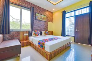 1 dormitorio con cama y pared de ladrillo en FabHotel Lotus en Udaipur