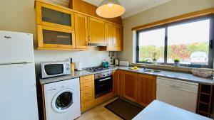 a kitchen with a washer and dryer and a microwave at White by Check-in Portugal in Albufeira