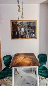 jadalnia z drewnianym stołem i zielonymi krzesłami w obiekcie Gold Apartament przy Księżym Młynie - Garaż - Dostęp na Kod - FV w Łodzi