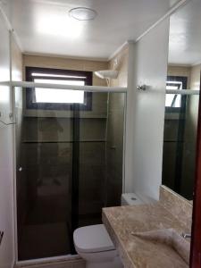 a bathroom with a toilet and a glass shower at Moderno Apartamento na Enseada com Wi-Fi e Vista Espetacular - Para Família e Home Office - 300m da praia in Guarujá