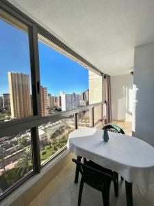 una mesa y sillas blancas en una habitación con una ventana grande en Los Gemelos 20 - Aloturin Benidorm, en Benidorm