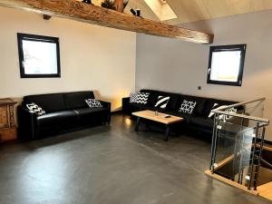 a living room with black leather couches and a table at Chalet Charbon in Boltigen