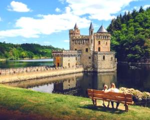 - un couple assis sur un banc devant un château dans l'établissement PLAISIR DES SENS, à Roanne