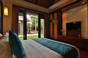 Schlafzimmer mit einem Bett, einem TV und einem Fenster in der Unterkunft Mahagiri Villas Sanur in Sanur