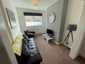 a living room with a leather couch and a television at Lovely Seaside House in Cleethorpes - sleeps 6 in Cleethorpes