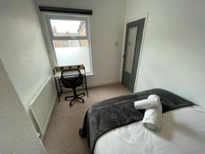 a bedroom with a bed and a desk and a window at Lovely Seaside House in Cleethorpes - sleeps 6 in Cleethorpes