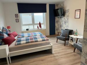 a bedroom with a bed and a window and a chair at Pension Blaue Nordseewelle in Neuharlingersiel