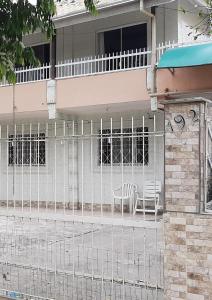 einen Zaun vor einem Haus mit zwei Stühlen in der Unterkunft Casas de Aluguel da Lulu in Itapema