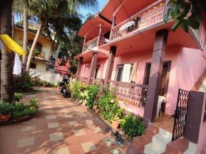 a pink building with plants in front of it at Camrose Guest House in Candolim