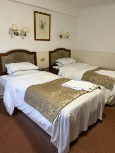 a hotel room with two beds with white sheets at The Saracens Head Hotel in Southwell