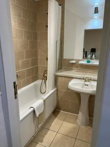 a bathroom with a sink and a tub and a toilet at The Saracens Head Hotel in Southwell