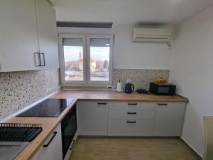 a small kitchen with white cabinets and a window at Studio SVACIC self check in in Osijek