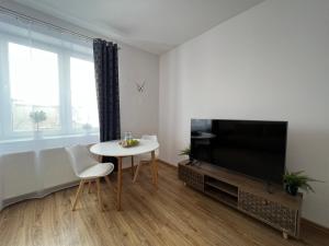 Nowe mieszkanie, fajna kamienica في بابيانيس: غرفة معيشة مع طاولة وتلفزيون وطاولة وكراسي