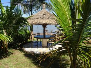 uma mesa com cadeiras e um guarda-sol de palha na praia em Coconut Beach em Majanji