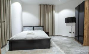 a bedroom with a large bed and a tv at 1125 City Apartment in Accra