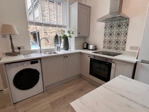 a kitchen with white cabinets and a sink and a dishwasher at Rose Cottage at The Stables in Stannington