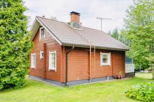 una pequeña casa de madera con un patio de césped en Countryside riverside cabin for both winter and summer for max 16 persons, en Janakkala