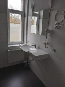 ein weißes Badezimmer mit einem Waschbecken und einem Spiegel in der Unterkunft Seehotel Krakow am See in Krakow am See