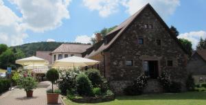 ein Steingebäude mit Sonnenschirmen davor in der Unterkunft Käfernberg - Weinhotel in Alzenau in Unterfranken