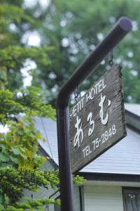 un cartel en un poste delante de una casa en HakubaGoryu Pension&LogCottage Arumu, en Hakuba