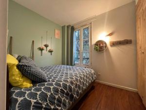 um quarto com uma cama com um edredão e uma janela em Le coin vert - 30'min de Paris 1km du RER em Chennevières-sur-Marne