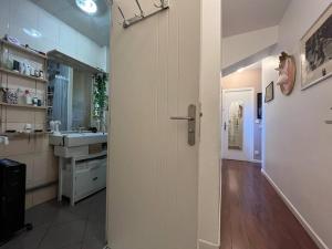 La salle de bains est pourvue d'un lavabo et d'une porte menant à une cuisine. dans l'établissement Le coin vert - 30'min de Paris 1km du RER, à Chennevières-sur-Marne