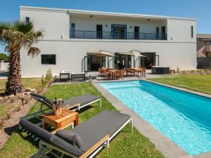 a villa with a swimming pool and a house at Glow Boutique Suites in Hermanus