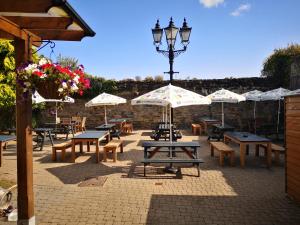 un gruppo di tavoli da picnic con ombrelloni su un patio di George & Dragon, Conwy a Conwy