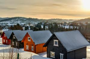 uma fila de casas na neve com o pôr do sol em Kolorowe Domki em Laliki