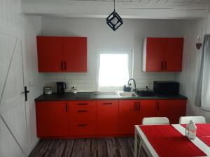 uma cozinha com armários vermelhos, um lavatório e uma janela em Kolorowe Domki em Laliki