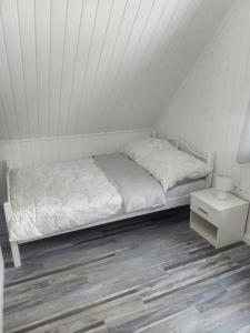 um quarto branco com uma cama e uma mesa de cabeceira em Kolorowe Domki em Laliki
