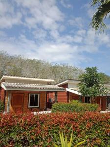 une maison avec des buissons rouges devant elle dans l'établissement Baan Saitharn Koh Lanta, à Ban Not (1)