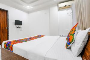 Dormitorio con cama blanca y almohada colorida en FabHotel Omkar Executive, en Pune