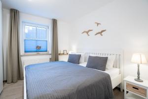 a white bedroom with a bed and a window at GAR4c Appartementhaus ""Seelust"" in Niendorf
